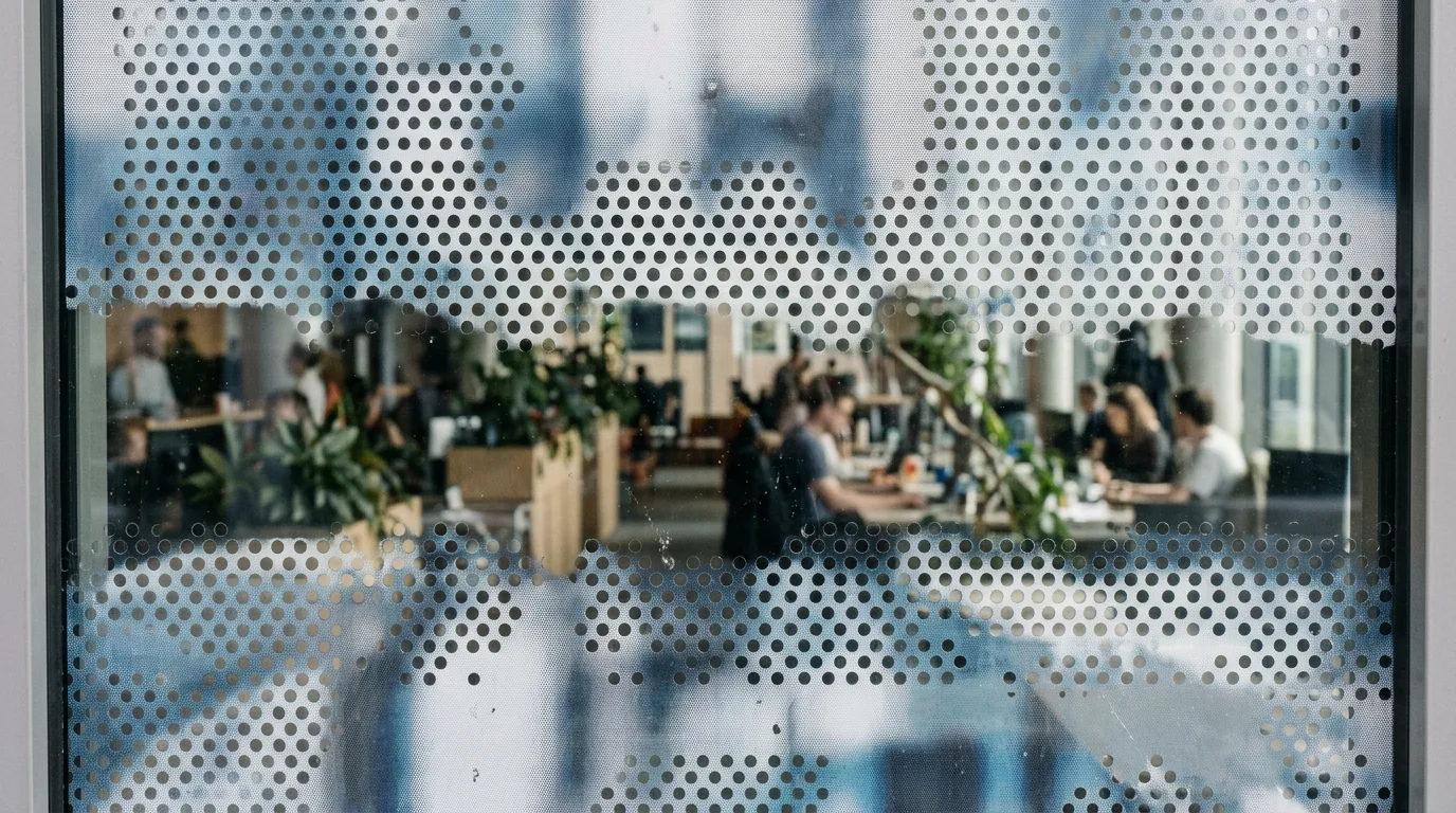Close-up van one way vision folie op een raam, met de perforaties en de bedrukte zijde zichtbaar.